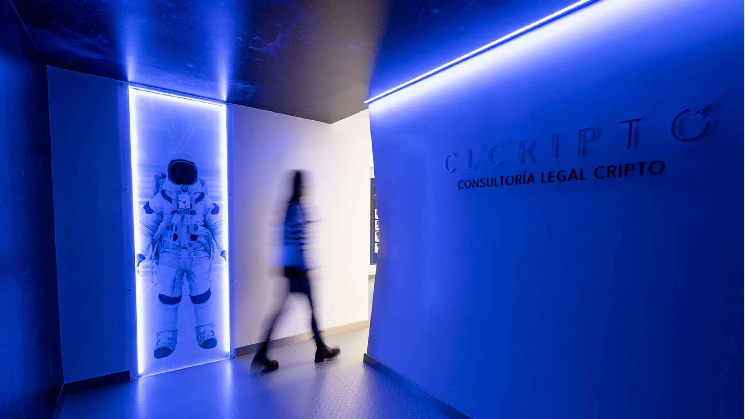 Entrada de las oficinas de CLCripto con luz azul, un astronauta retroiluminado en la pared y el logotipo de la marca