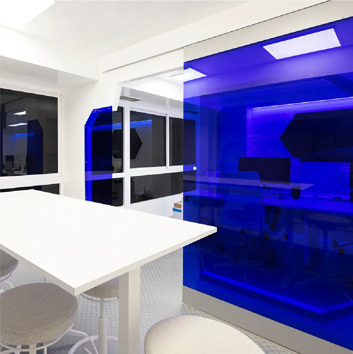 Mesa blanca junto a un cerramiento de cristal azul iluminado en las oficinas de CLCripto
