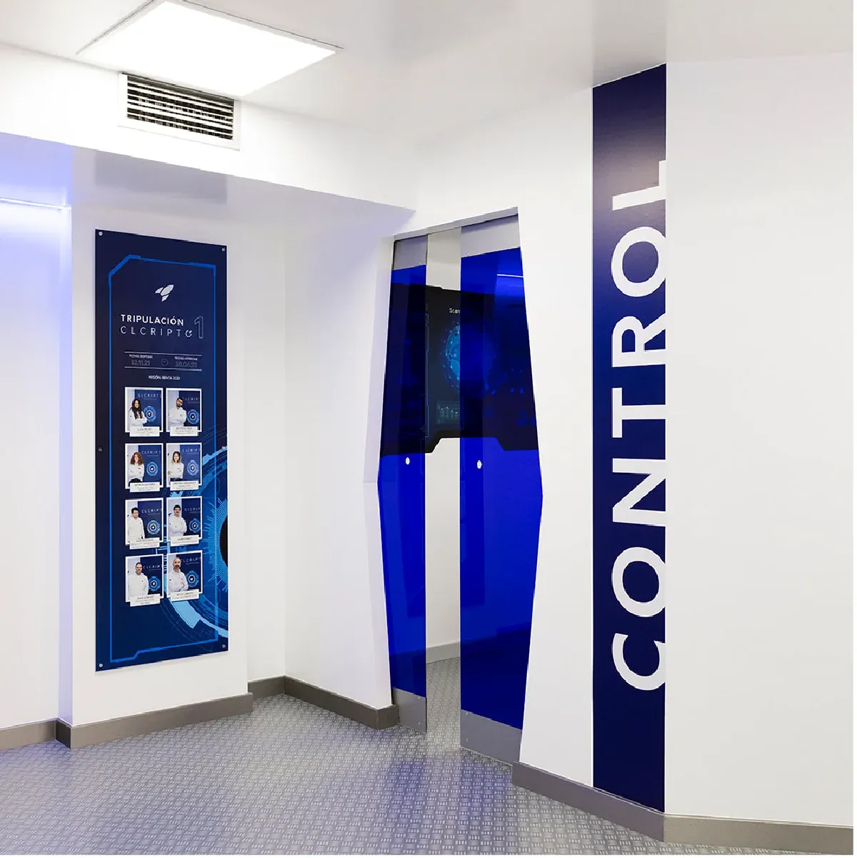 Pasillo de las oficinas con el rótulo vertical «Control» y un panel informativo de CLCripto